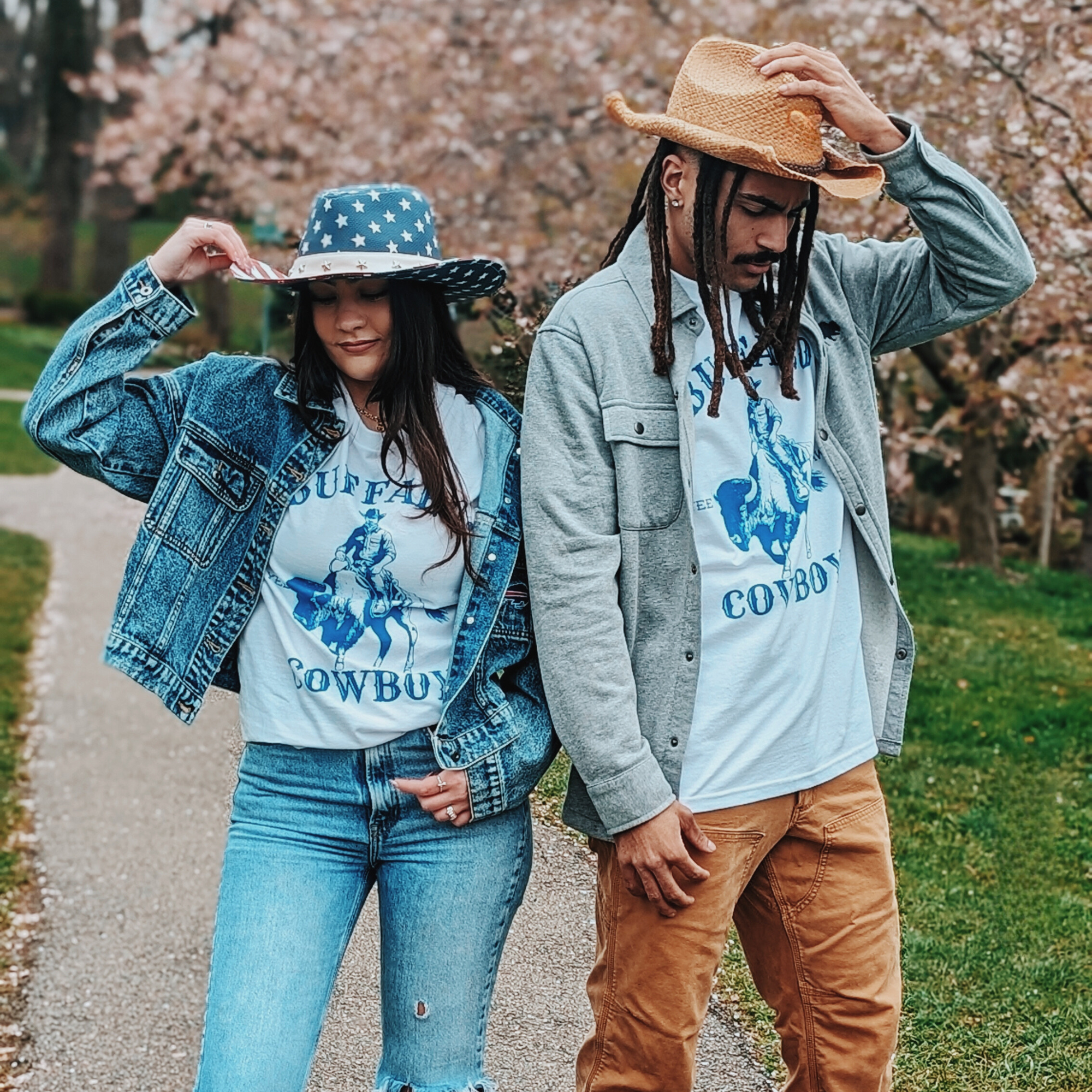 a guy and a girl posing for a picture while wearing cowboy hats and shirt that says buffalo cowboy with a cowboy riding a buffalo