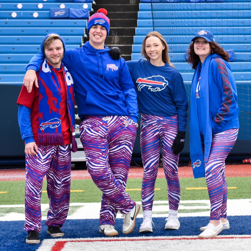 Men and women wearing Buffalo Bills apparel. They are at Highmark Stadium. This image is the The BFLO Store website.