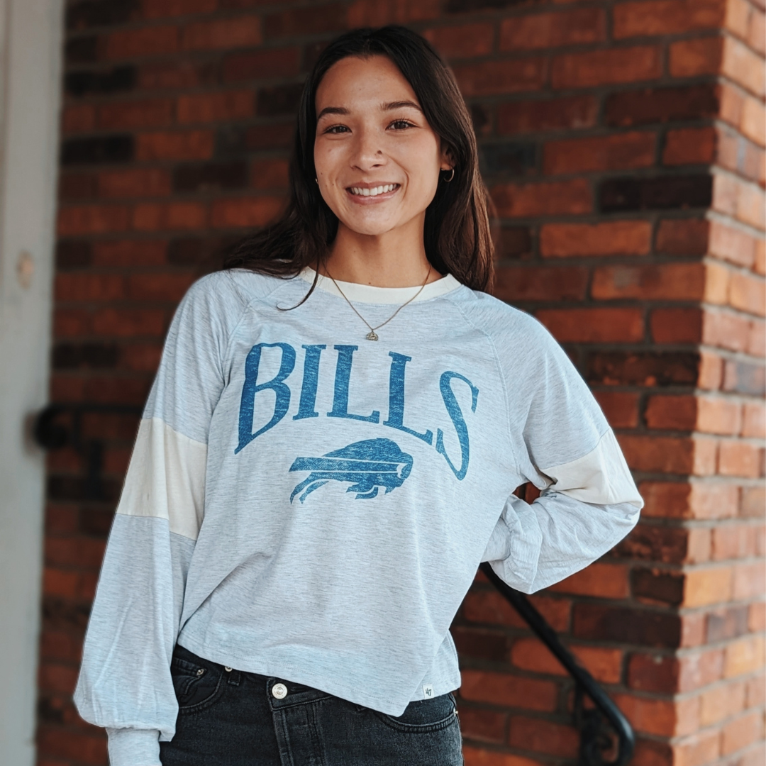 woman posing for a picture wearing a light gray and blueish long sleeve buffalo bills shirt