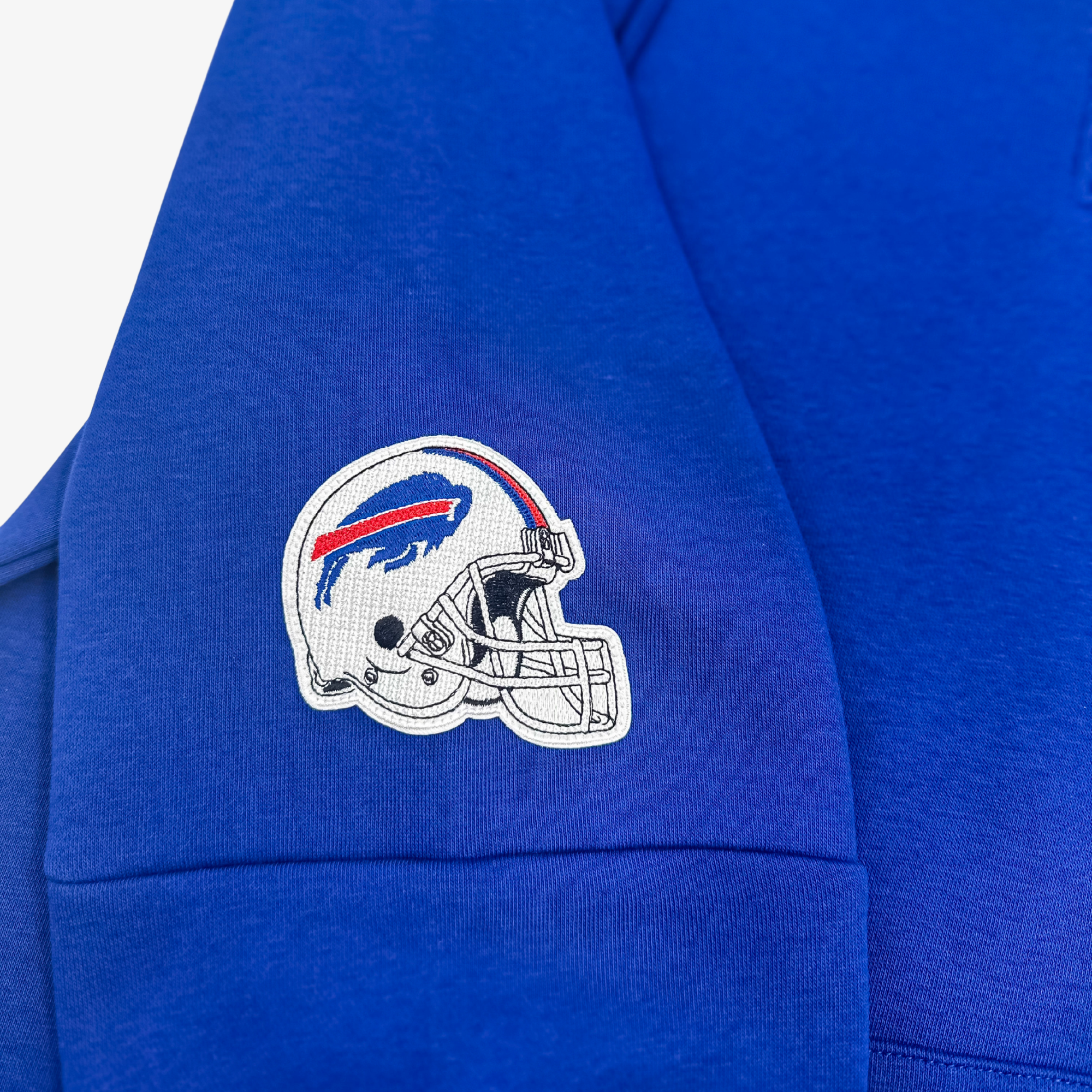 Close-up of a royal blue sweatshirt sleeve featuring an embroidered Buffalo Bills helmet logo patch on the upper arm.
