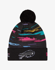 A black knit pom-pom beanie with a colorful abstract stripe pattern in pink, blue, yellow, and purple, featuring a white Buffalo Bills logo on the cuff.