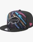 A black New Era 9FIFTY snapback cap featuring a colorful abstract paint stroke pattern on the front panels and a white embroidered Buffalo Bills buffalo logo on the side. The cap has a black flat brim with a silver sticker, and a pink New Era logo is visible on the side.
