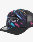 A black New Era 9FIFTY trucker hat featuring a colorful paint stroke pattern in pink, blue, and yellow on the front panels, with a black embroidered Buffalo Bills charging logo and a pink New Era logo on the side.