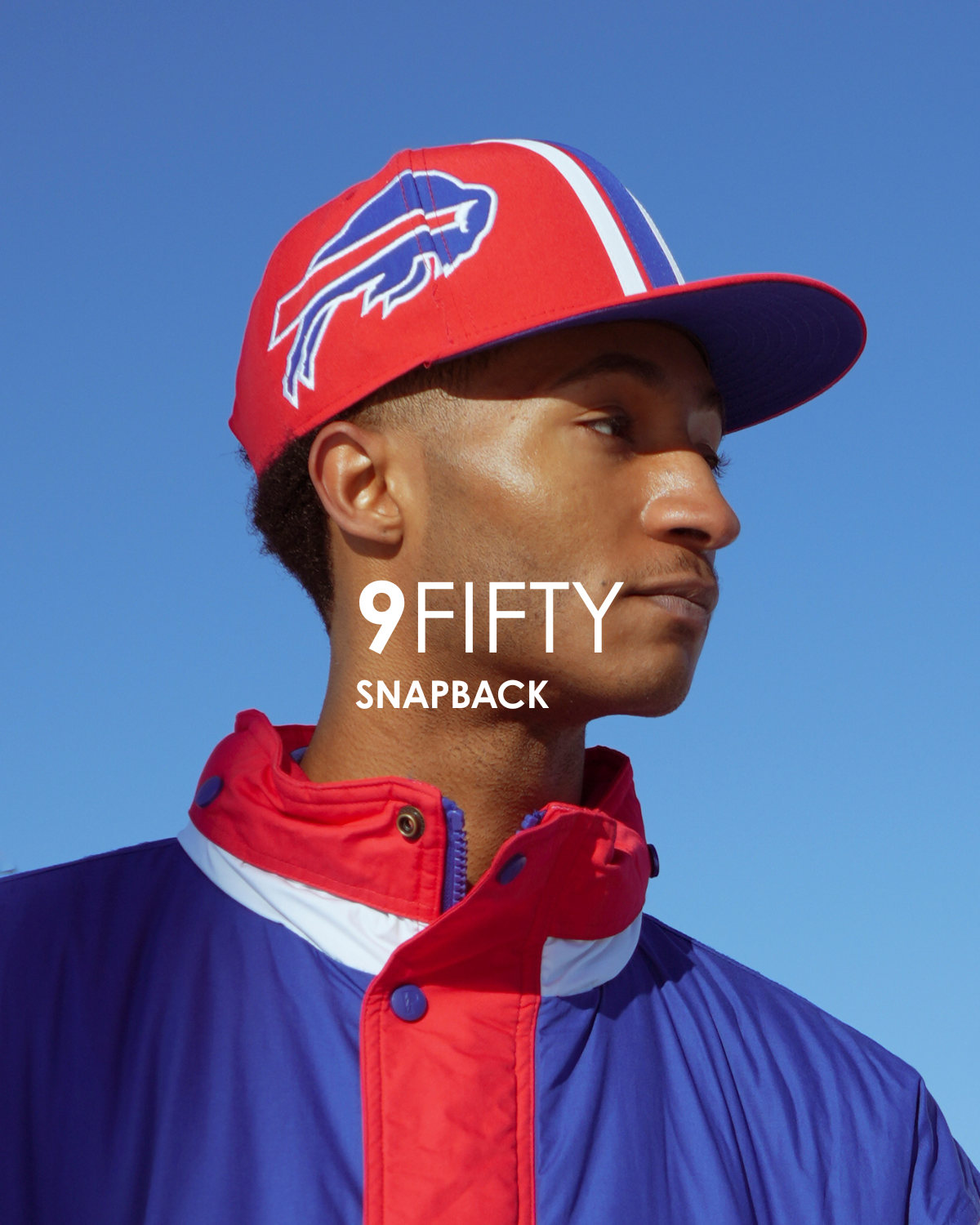Person wearing a red and blue sports cap with a logo, against a clear blue sky that is titled 9fifty snapback.
