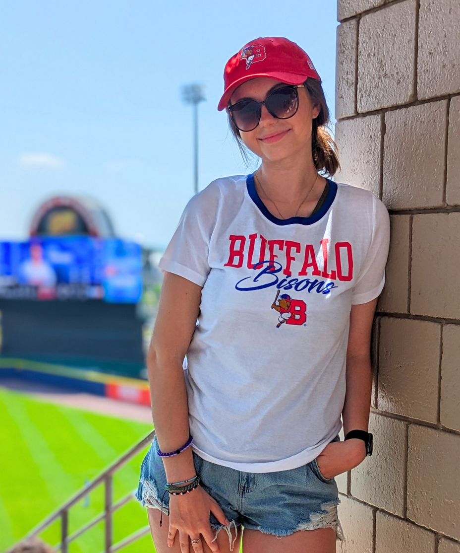 woman at a bisons game wearing a buffalo bisons white short sleeve shirt and red bisons hat