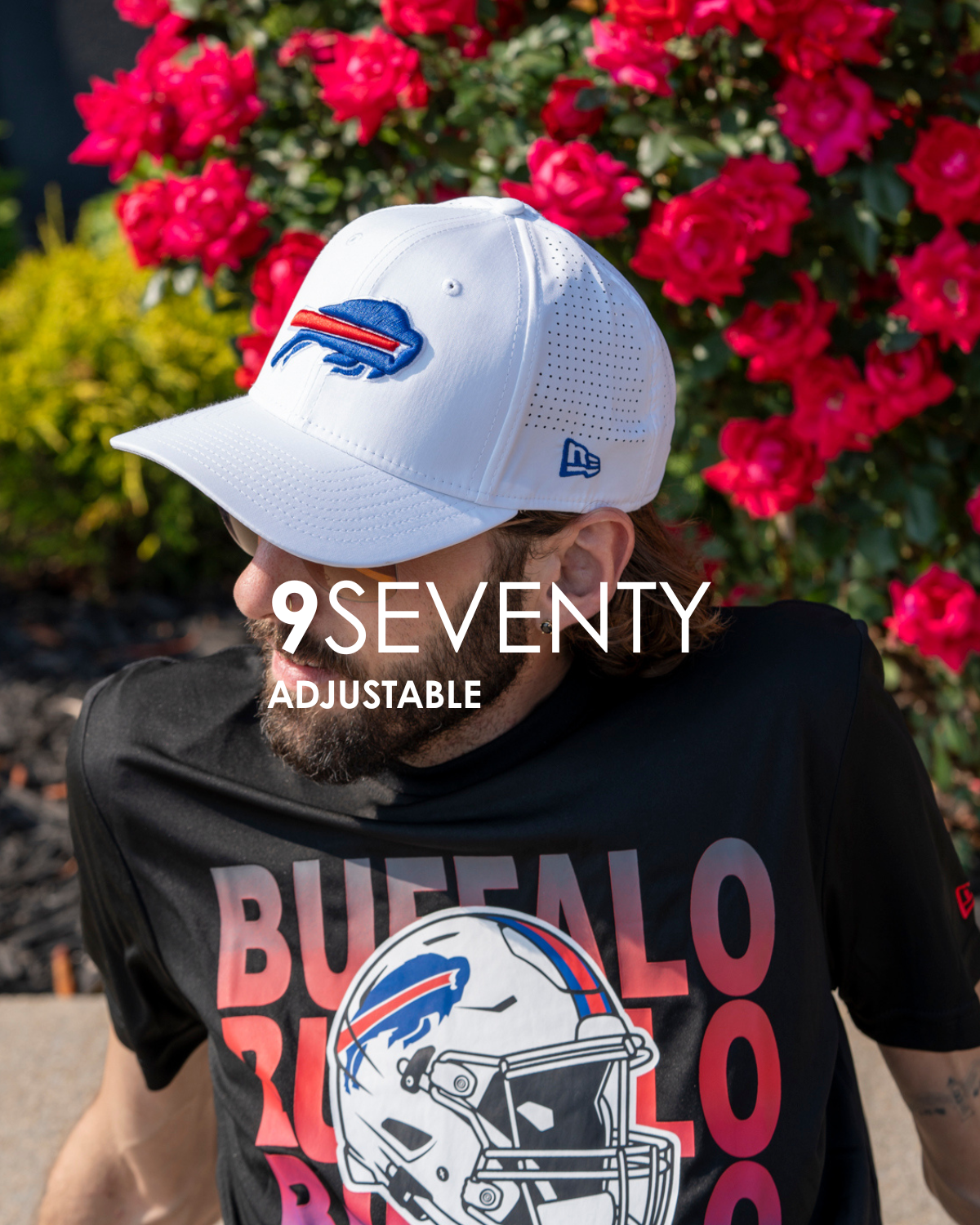 Person wearing a white cap with a logo and a black t-shirt with a helmet design, standing in front of pink flowers that is titled 9seventy adjustable.