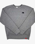 A heather gray crewneck sweatshirt with a small black bison logo on the left chest and a small red tag near the bottom hem, shown flat on a light gray background.
