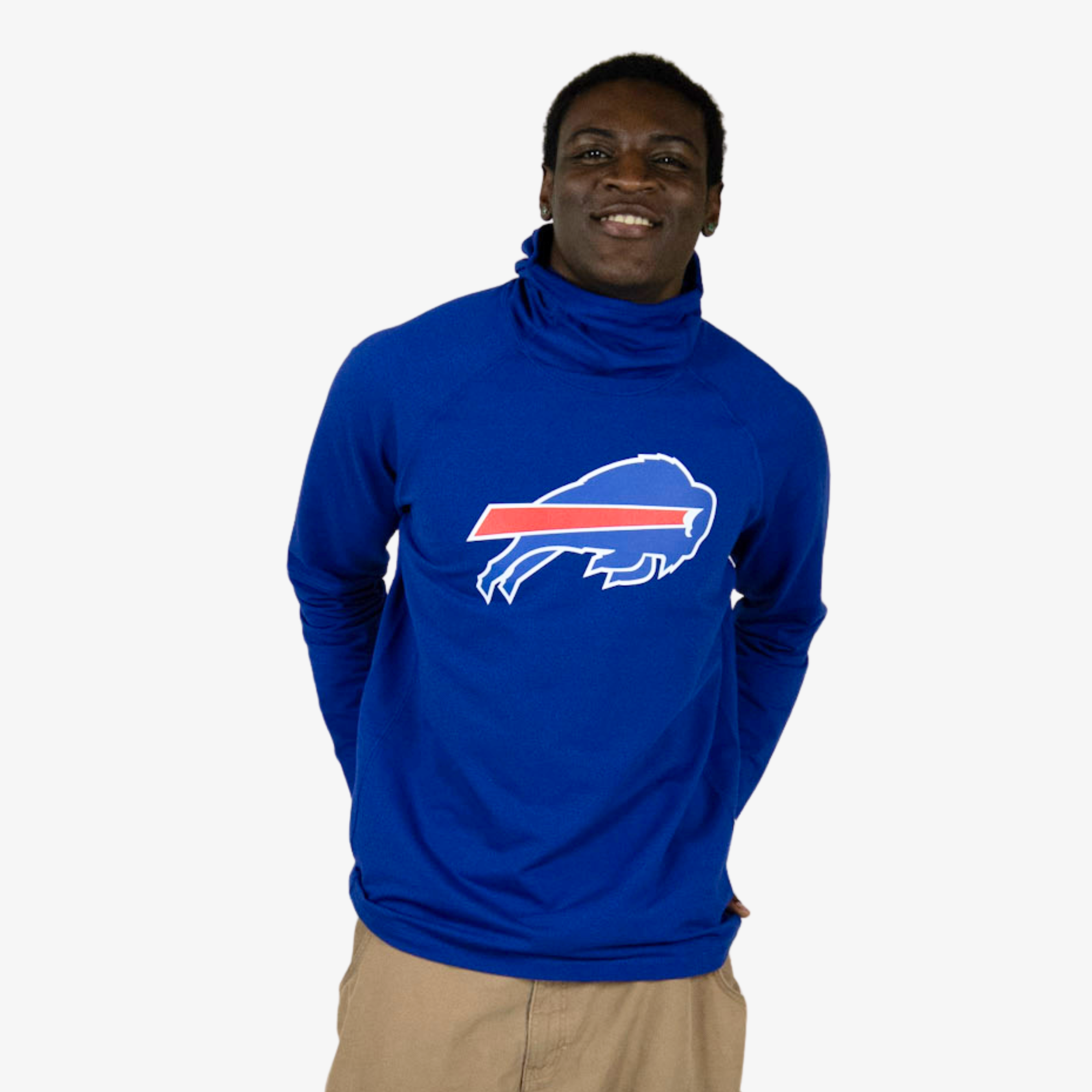 A man wearing a royal blue long-sleeve turtleneck pullover with a white and red Buffalo Bills charging buffalo logo on the chest, paired with khaki pants, against a plain white background.