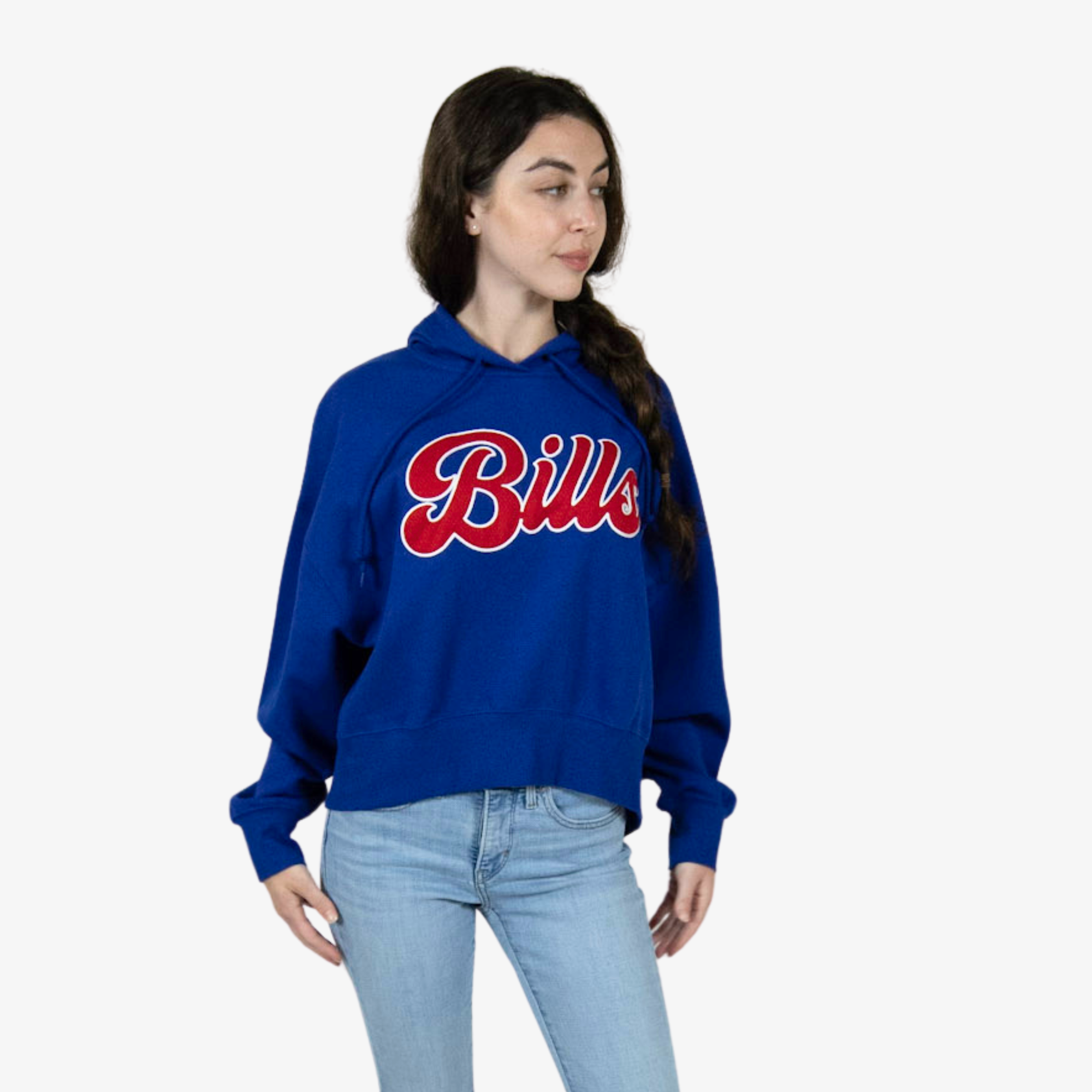 A woman wearing a royal blue cropped hoodie with 'Bills' written across the chest in red and white script, paired with light blue jeans, set against a plain light gray background.