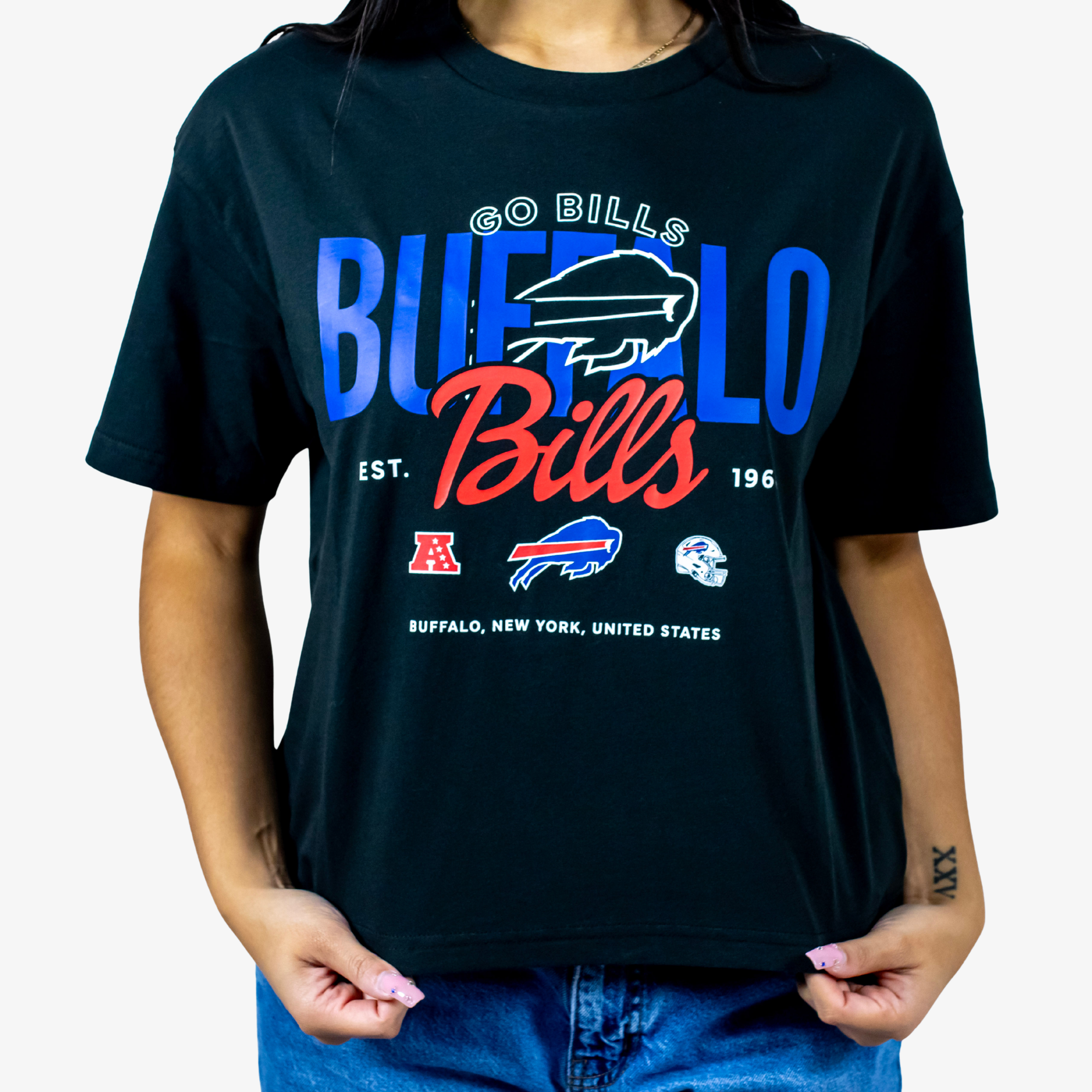 A person wearing a black Buffalo Bills graphic t-shirt with blue and red lettering, paired with blue jeans, against a plain white background.