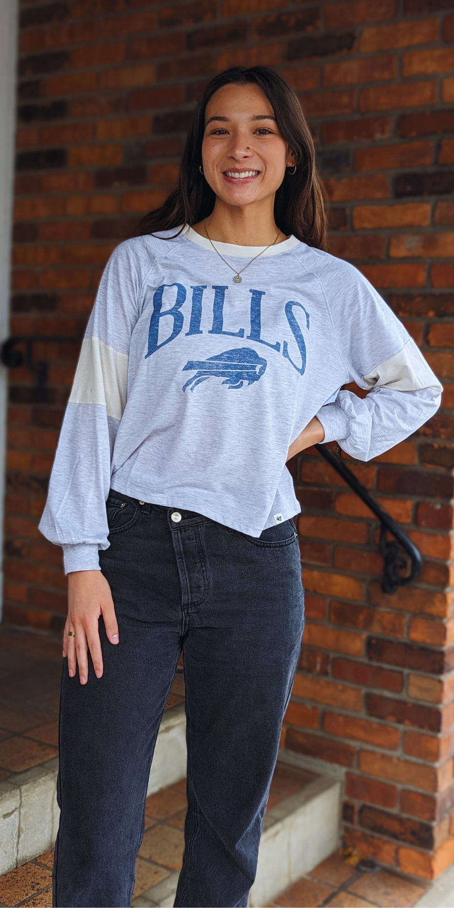 woman posing for picture wearing a gray buffalo bills long sleeve shirt