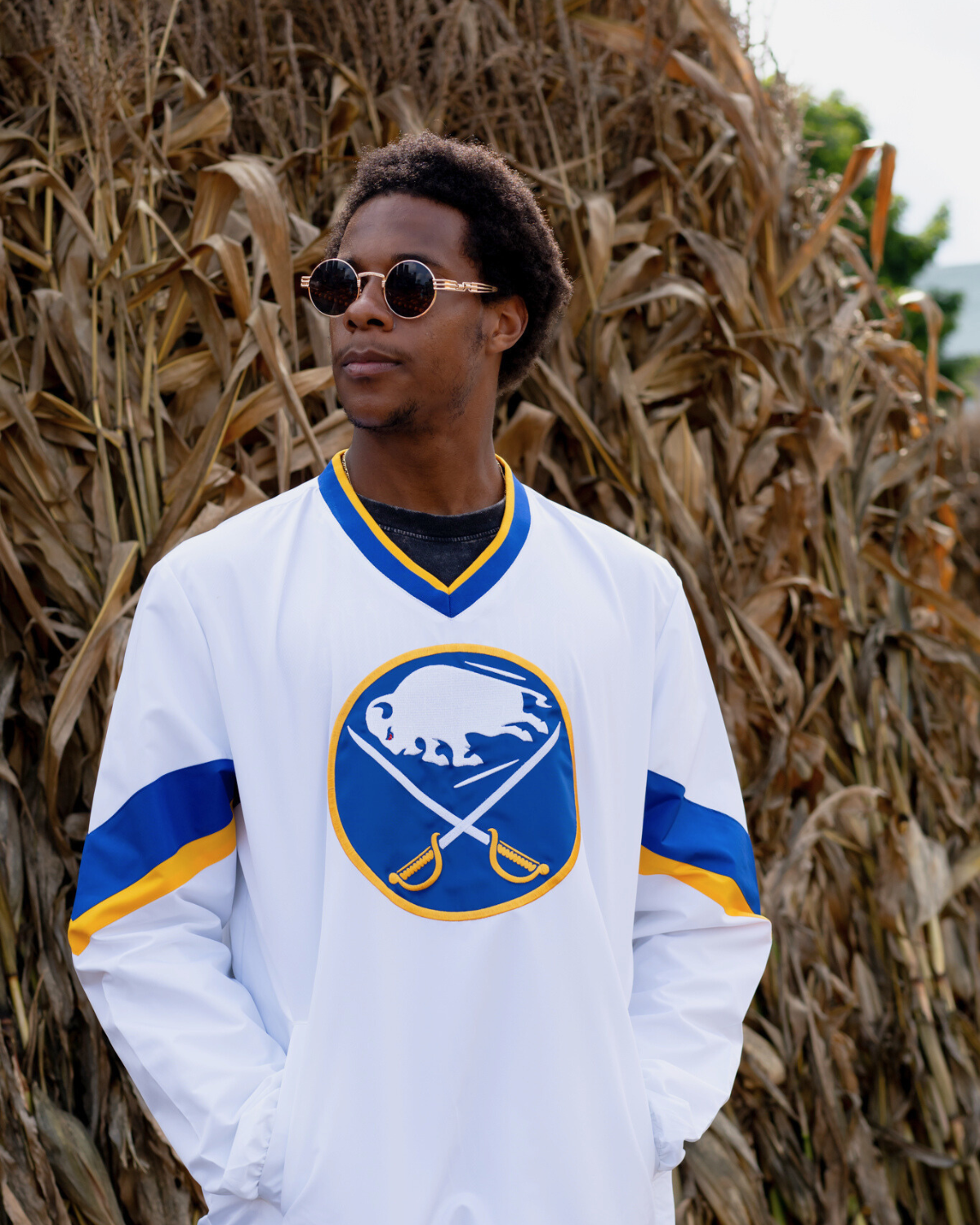 man wearing a buffalo sabres white crewneck jacket in a cornfield. link to mens buffalo sabres apparel