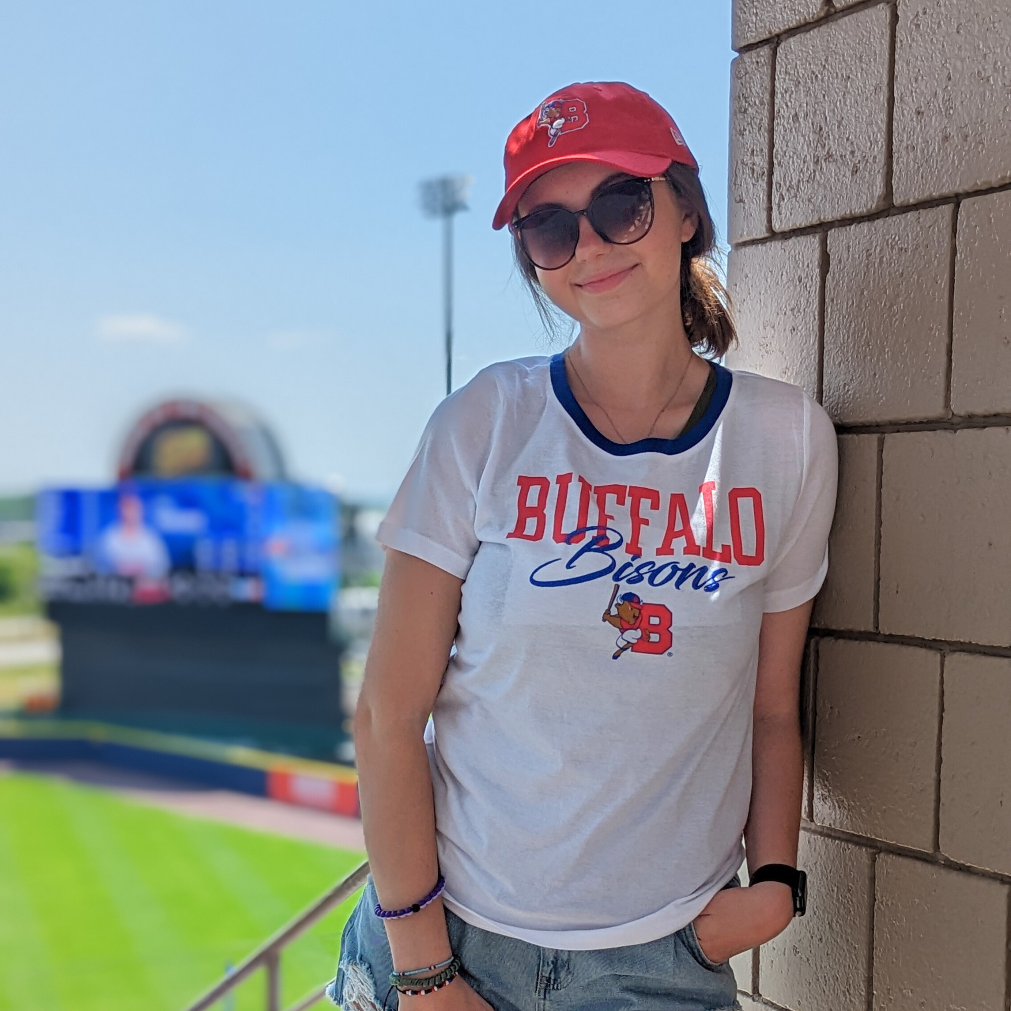 women posing for a photo at a baseball game wearing buffalo bisons apparel