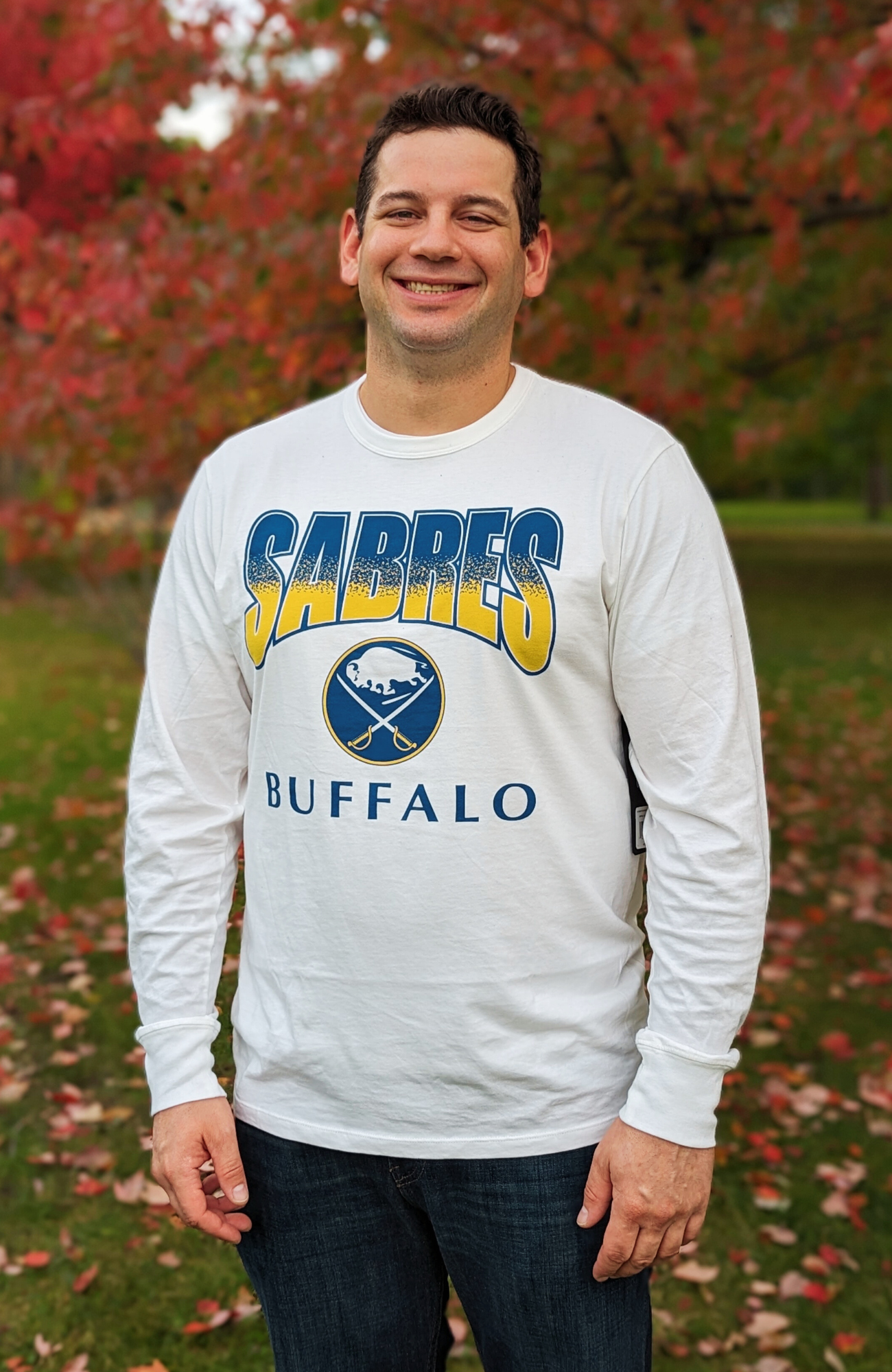 man posing for a picture in the park wearing a buffalo sabres long sleeve shirt
